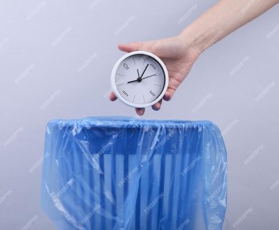 hand-throws-clock-into-trash-bin-with-package-gray-background_175682-36679